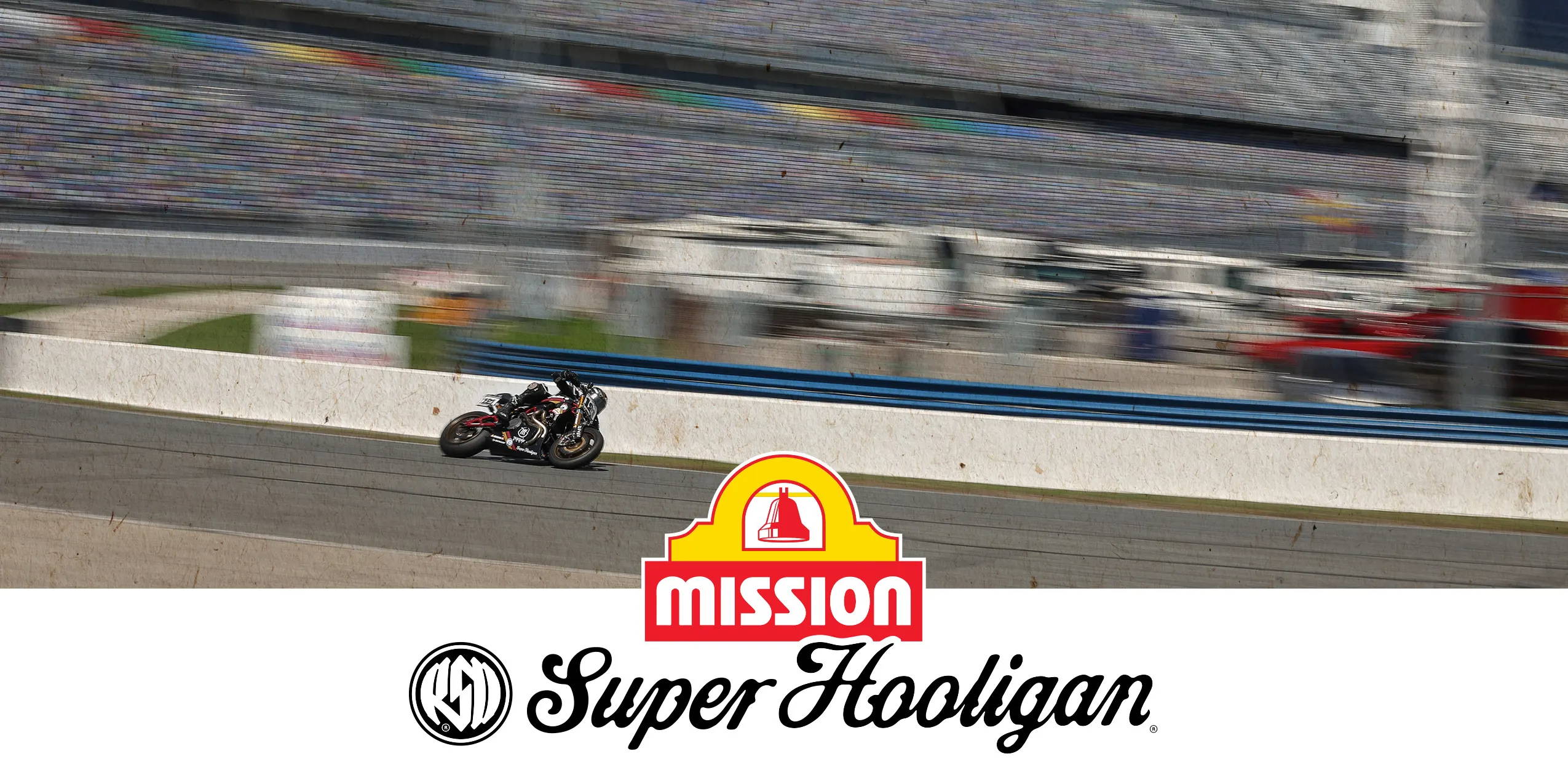 A motorcycle racer speeds along the high banks of Daytona International Speedway in the Super Hooligan race, captured in front of a colorful, blurred crowd in the grandstands. Prominent overlays include the Mission Super Hooligan logo, highlighting the high-octane excitement of the event.