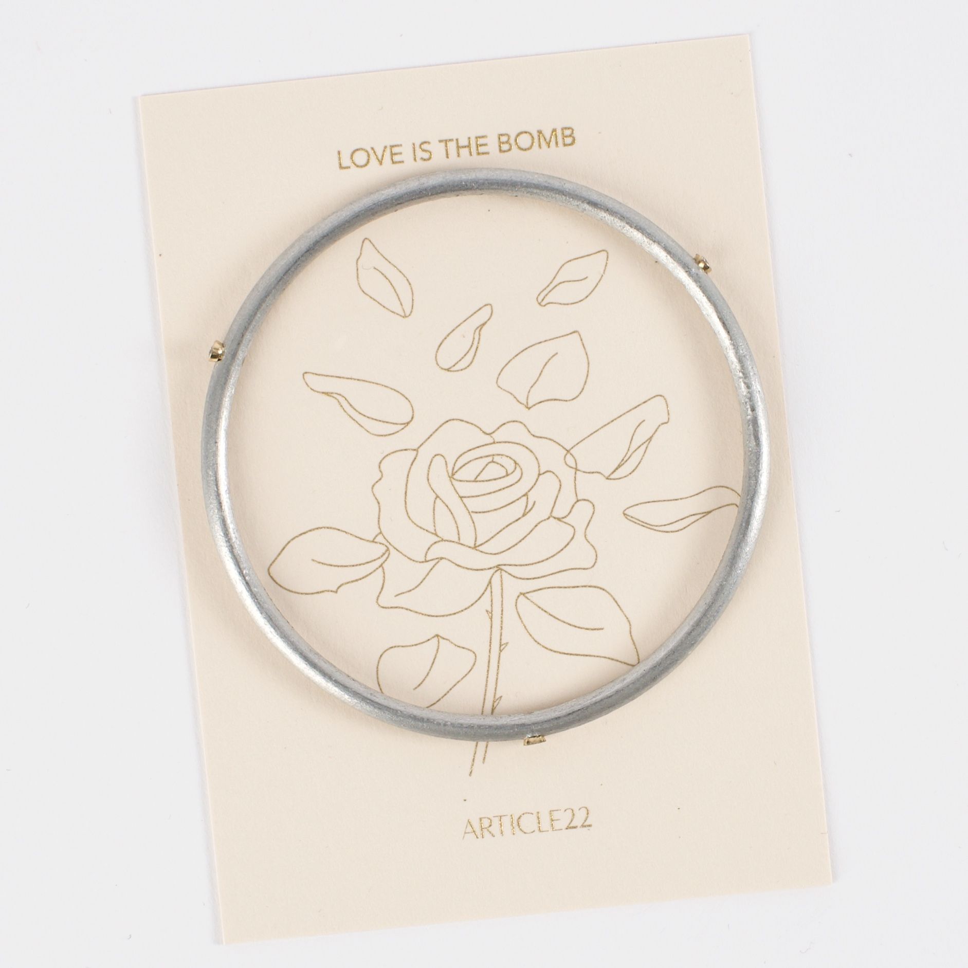 A silver bracelet with diamonds on a card with a rose design symbolizing love.