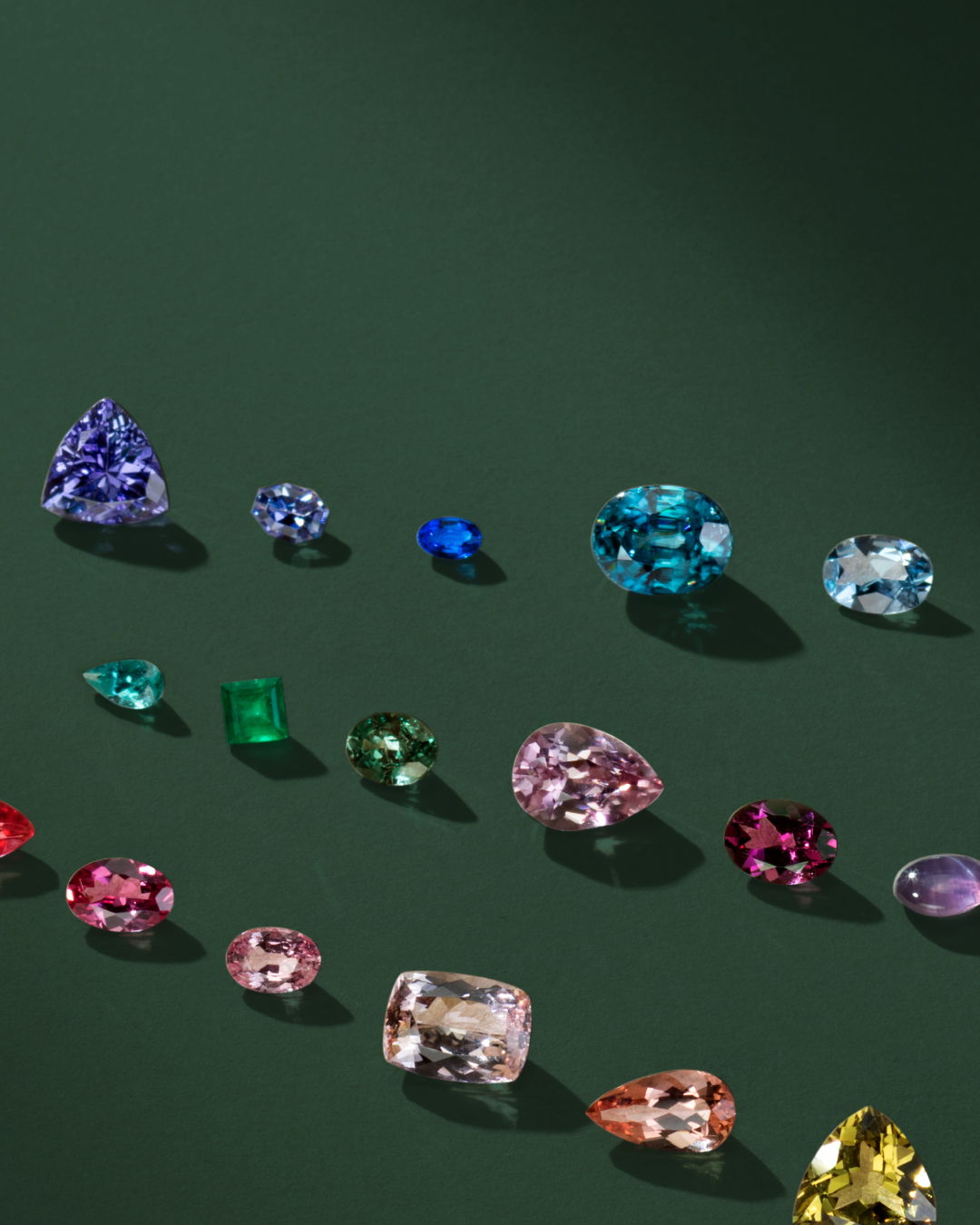 A variety of colorful gemstones arranged on a dark green background.