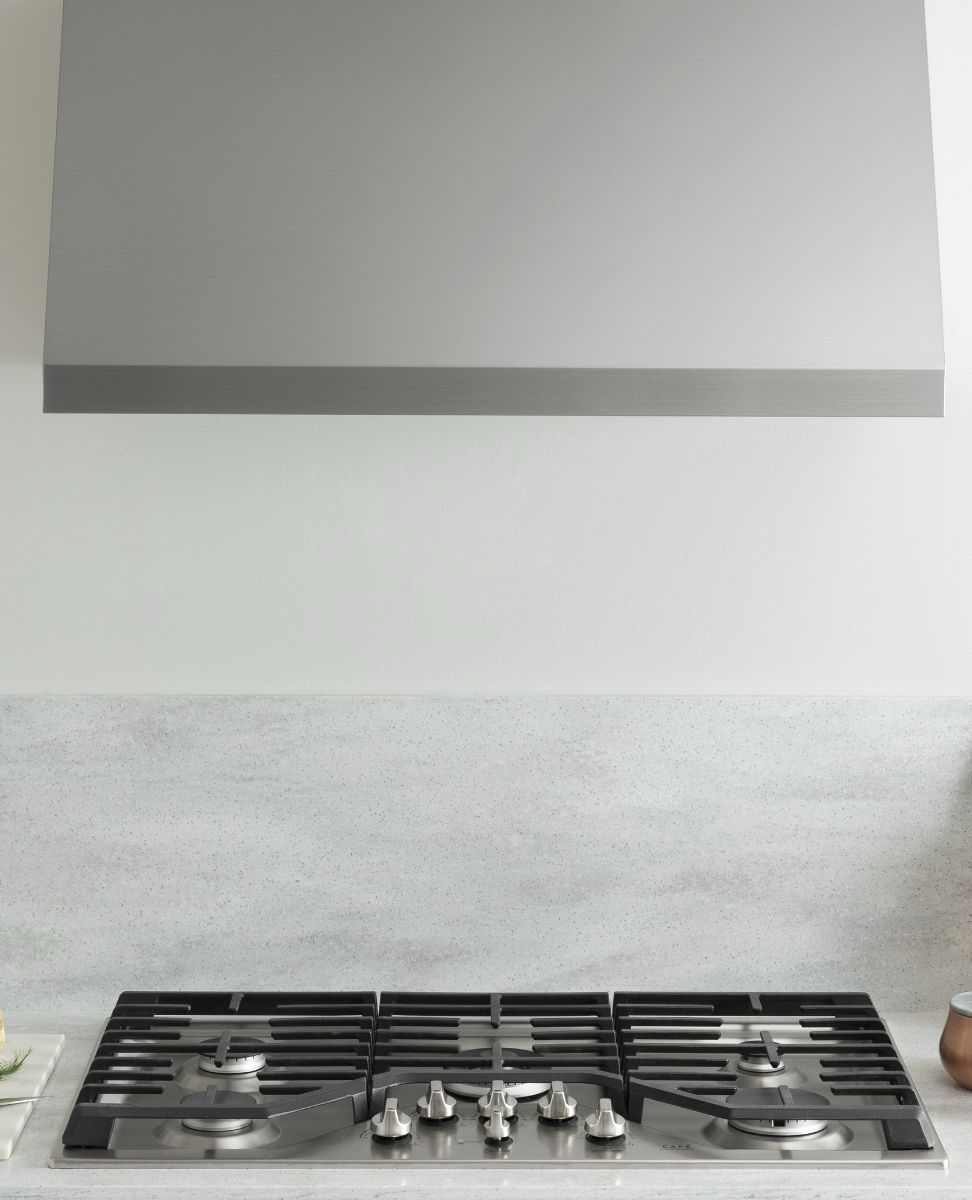 Modern kitchen with a stainless steel hood and gas stovetop.