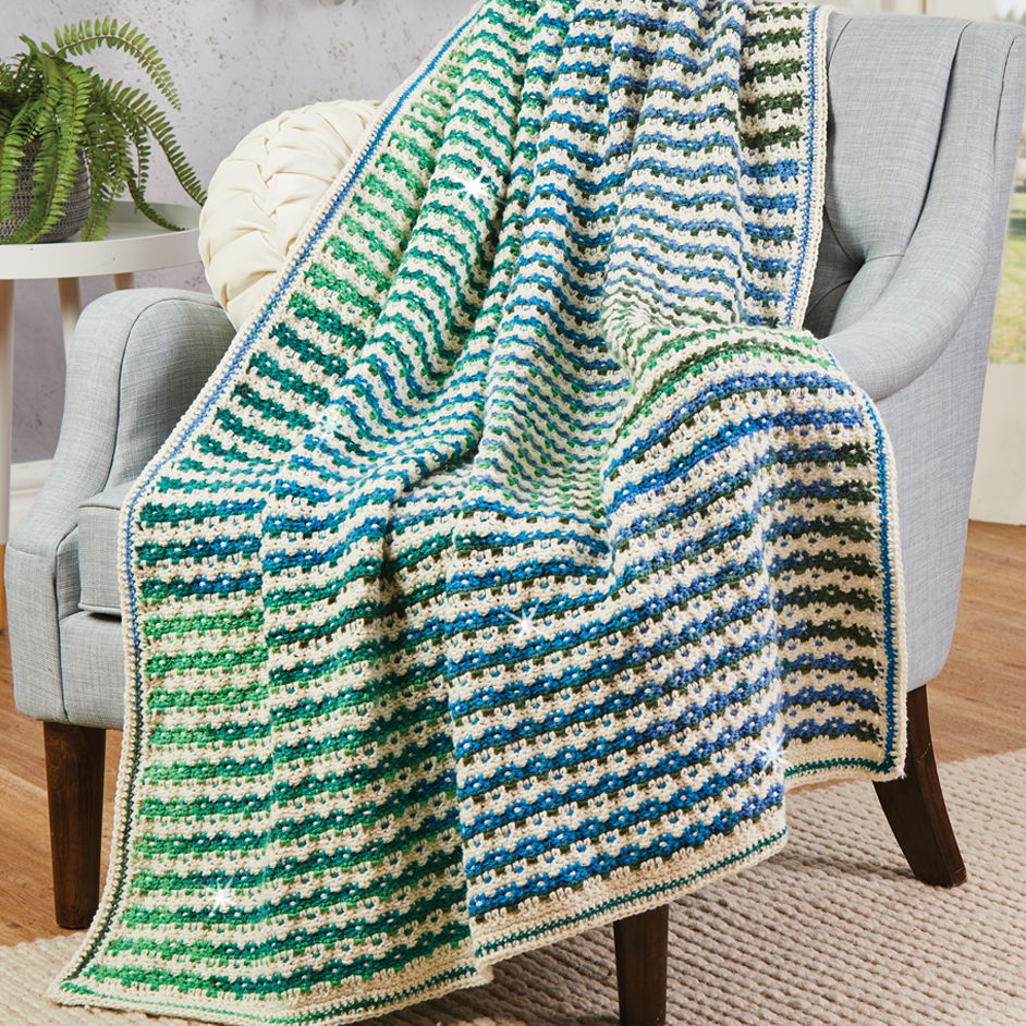 A colorful blanket draped over a chair, featuring stripes of green and blue.