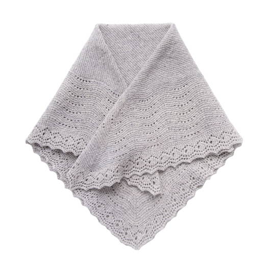 Folded flat of a delicate lace hand knit shawl in wool yarn