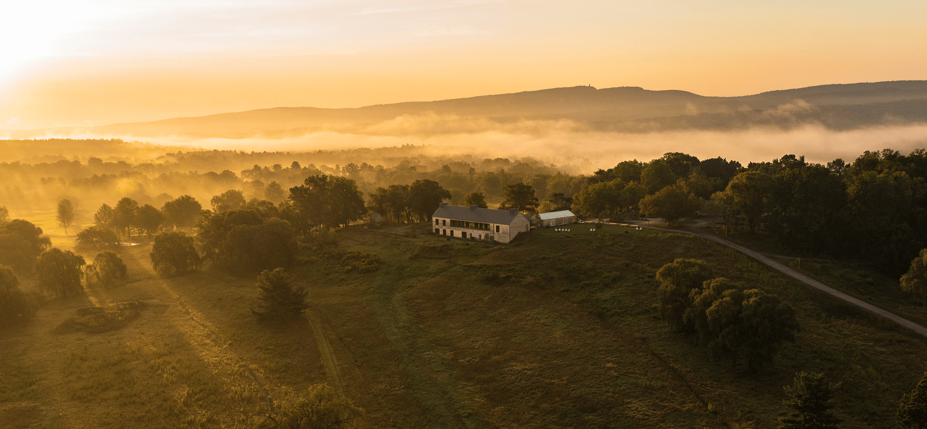 Aerial view of a serene landscape at sunrise with mist.
