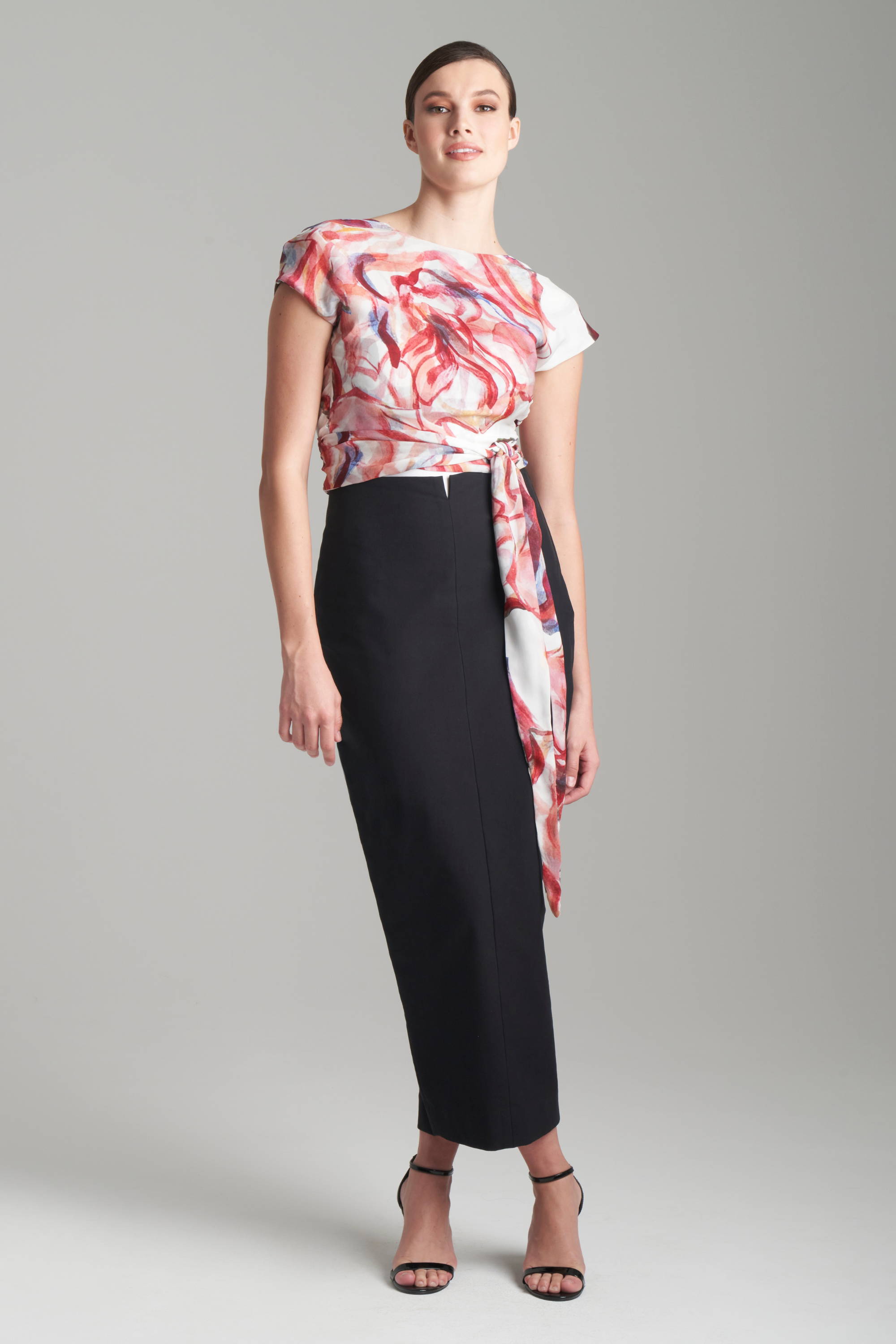 Woman wearing red and white reversible silk wrap top with black cotton pencil skirt by Ala von Auersperg