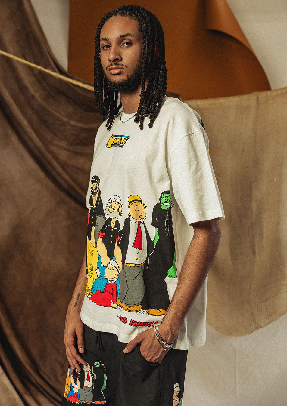 Person wearing a graphic t-shirt with cartoon characters, standing in a stylish setting.