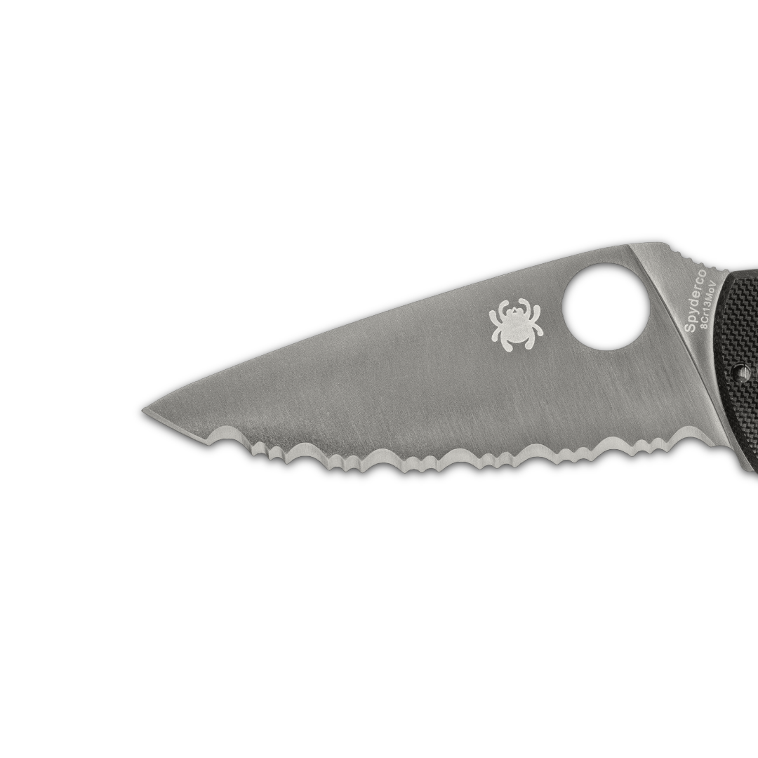 A close-up of a serrated knife blade with a spider logo.