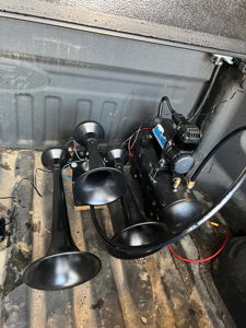 Three black train horn trumpets and air compressor system installed in the bed of Jimmy's Ford F250