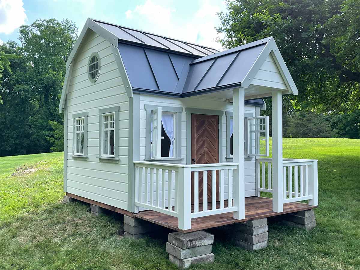 Black and white Wooden Playhouse with wooden Porch with white handmade railing by WholeWoodPlayhouses
