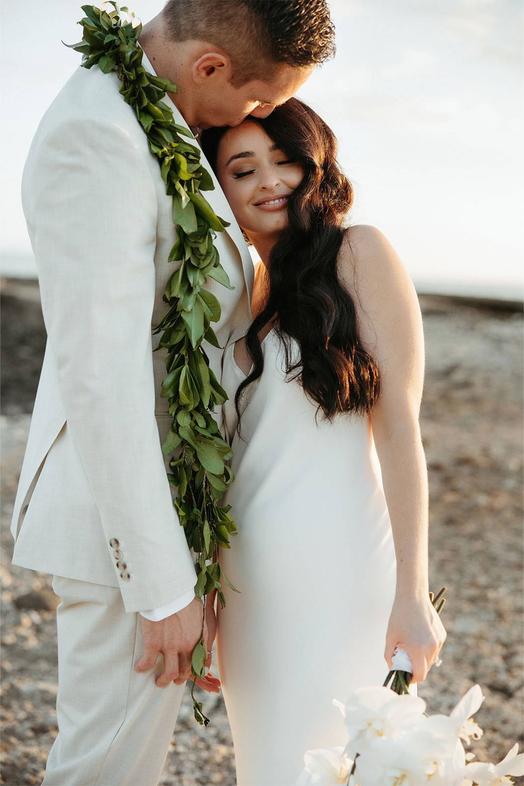 Groom with leafy lei on shoulders