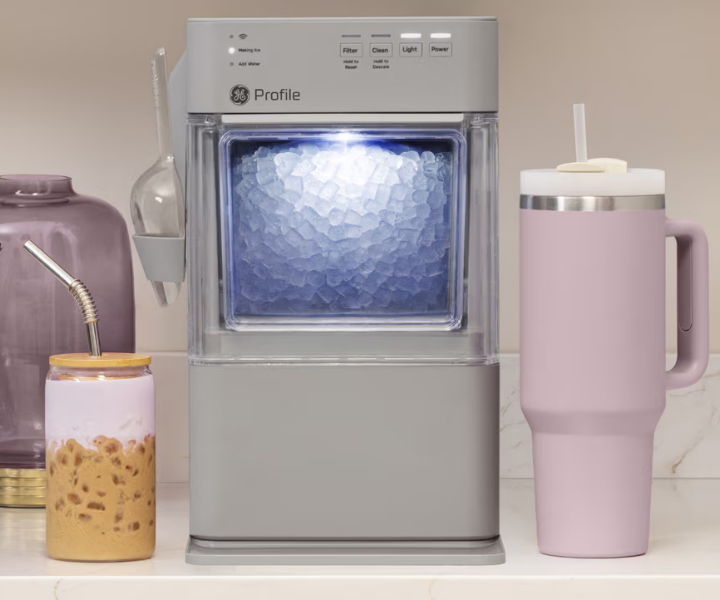 A countertop ice maker next to colorful drink containers.