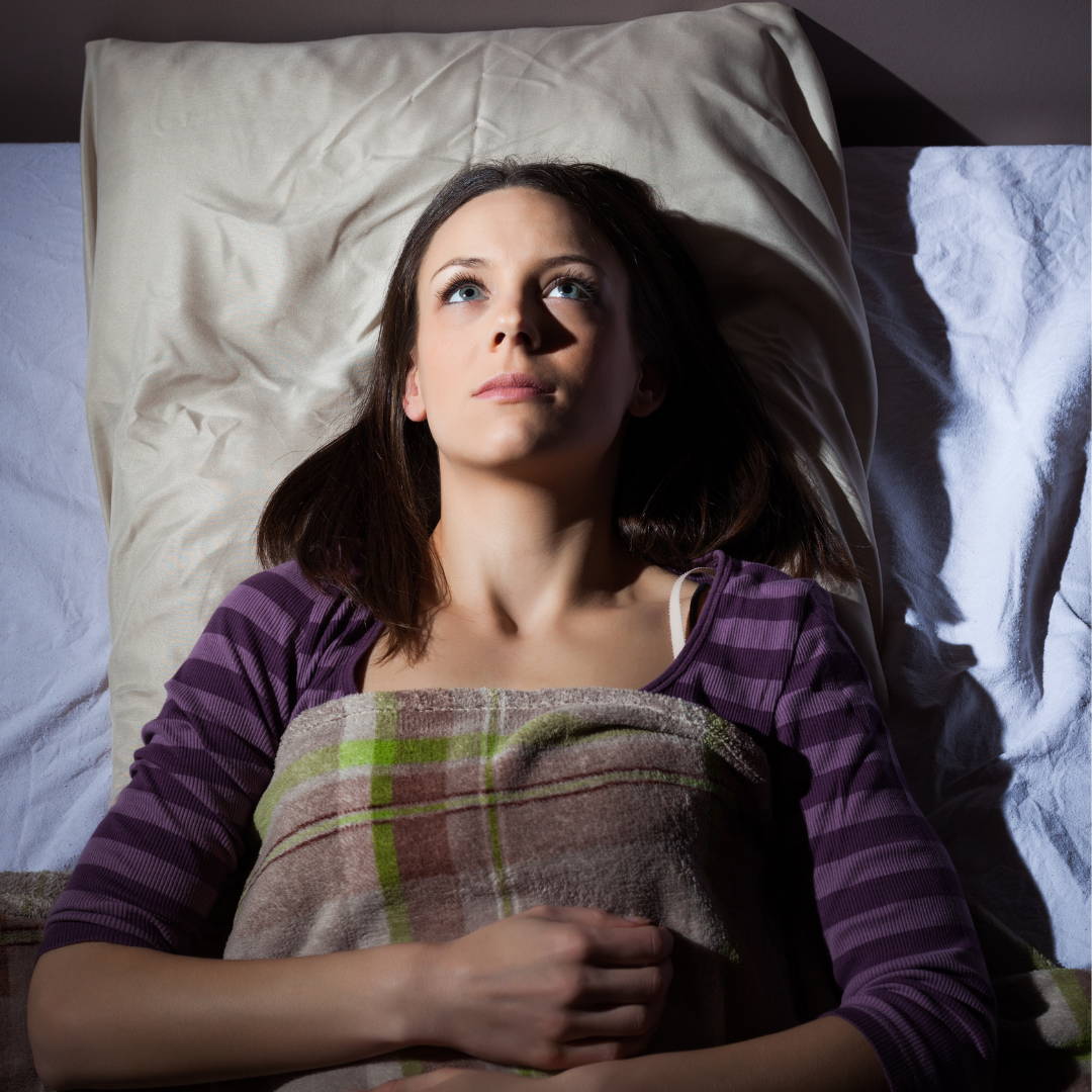 A woman lying asleep in her bed wide awake.