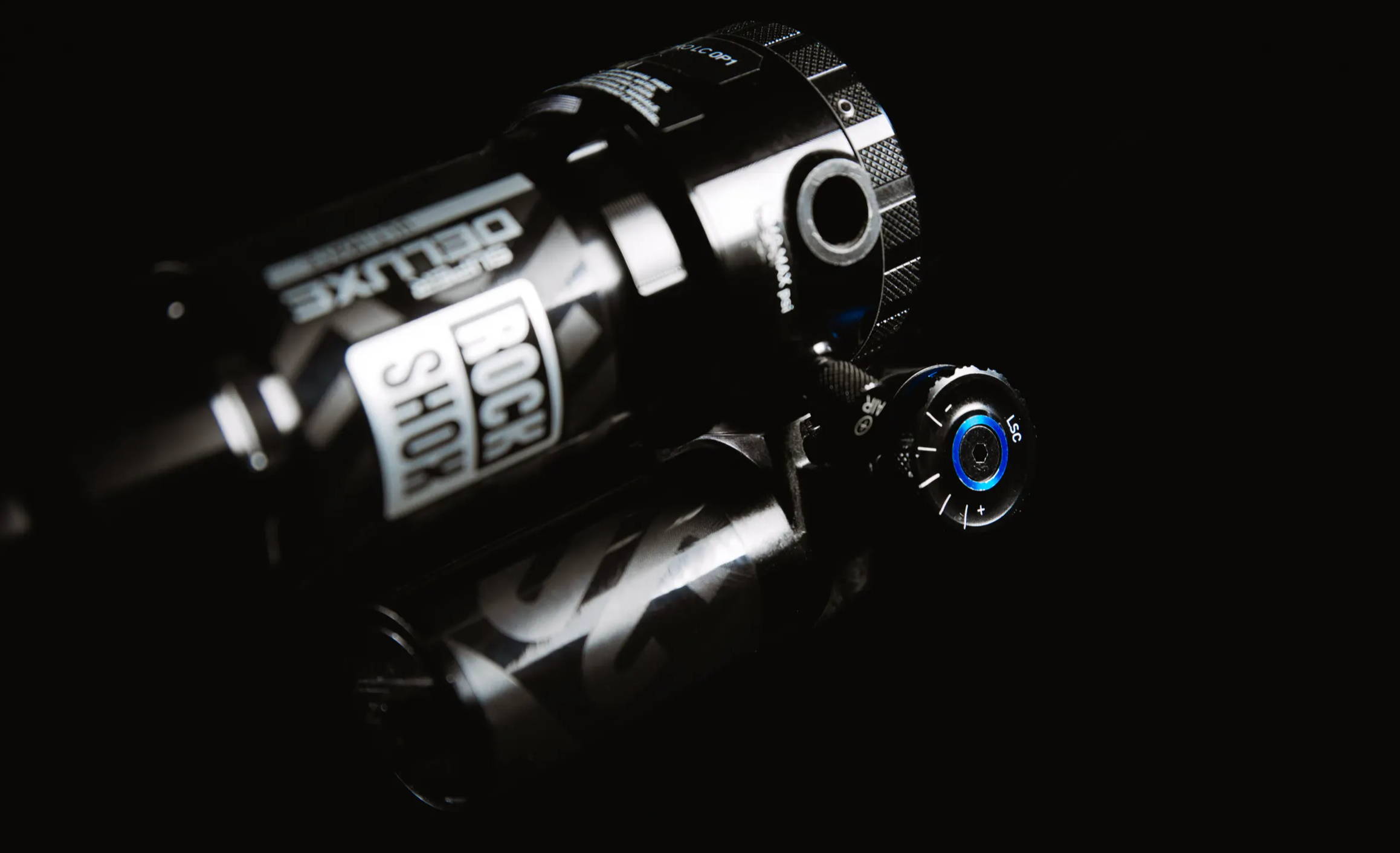 detail of the low speed compression knob on the rockshox super deluxe ultimate mountain bike rear shock on a black background