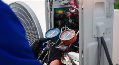 Technician checking air conditioning system with pressure gauges.