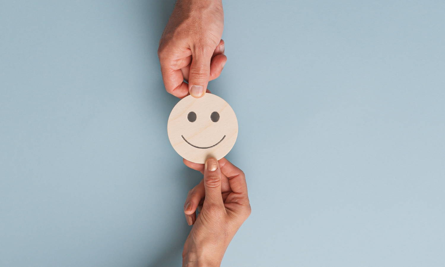 hands holding a smiley face between them for customer feedback
