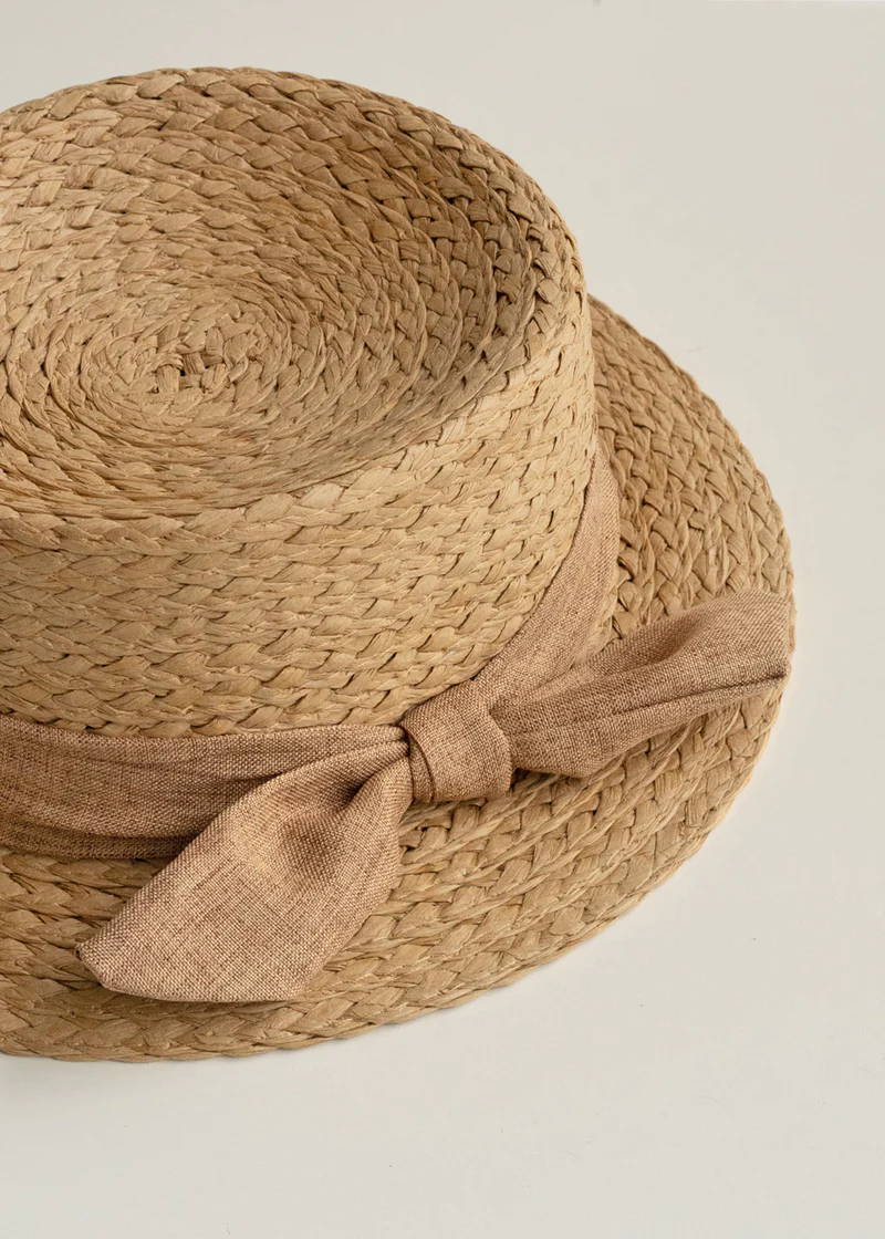 A wicker round brimmed hat with beige ribbon detail 