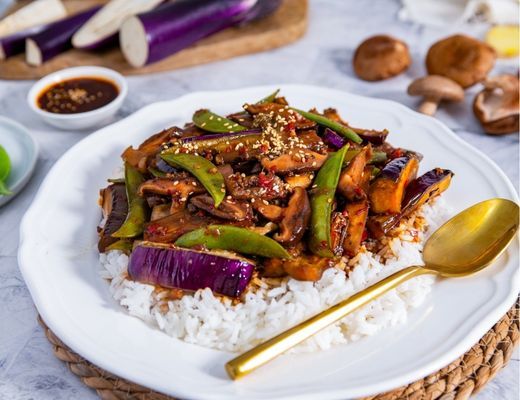 A plate of rice topped with vegetables and sauce.