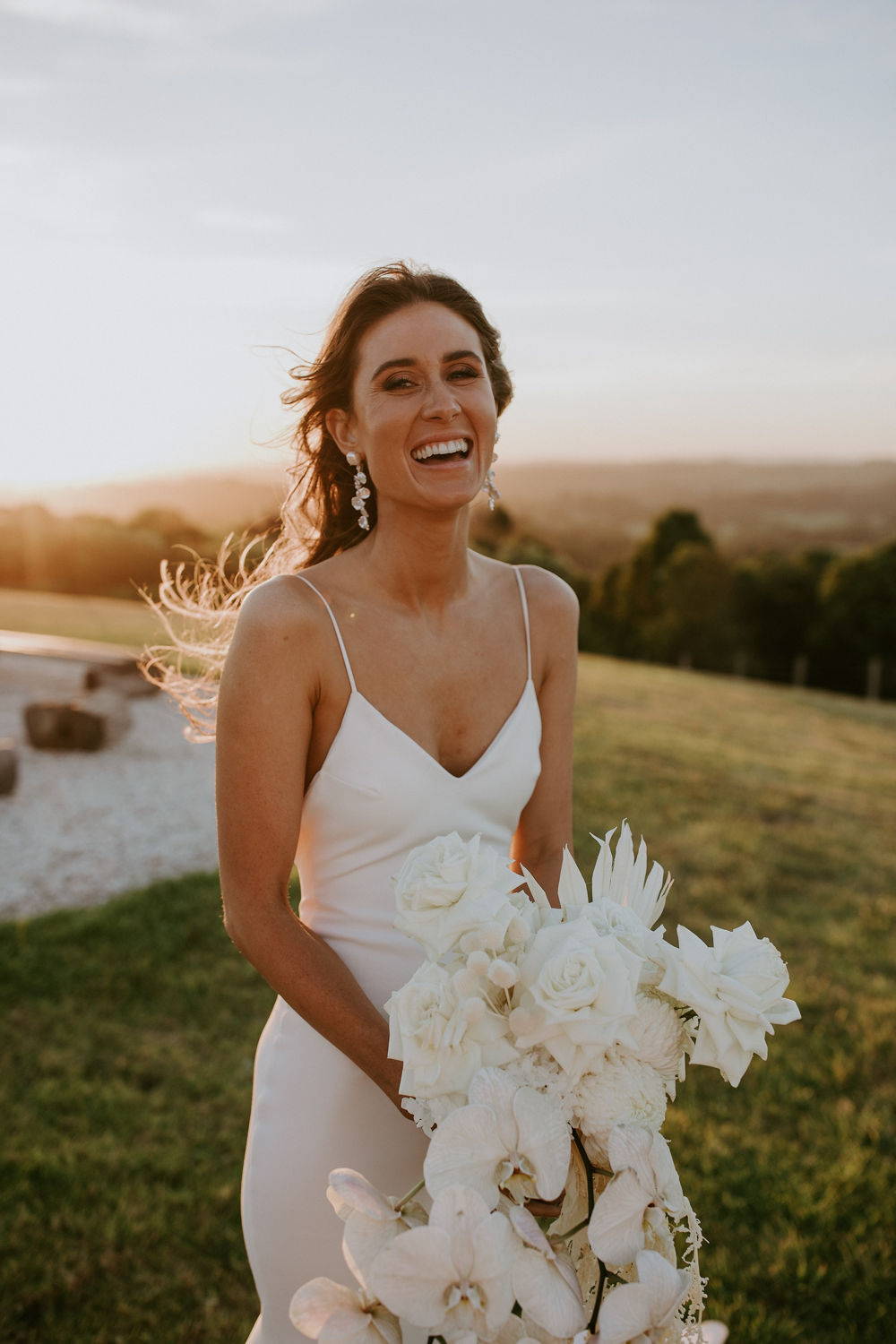 La novia lleva un vestido de seda con escote en V y flores blancas