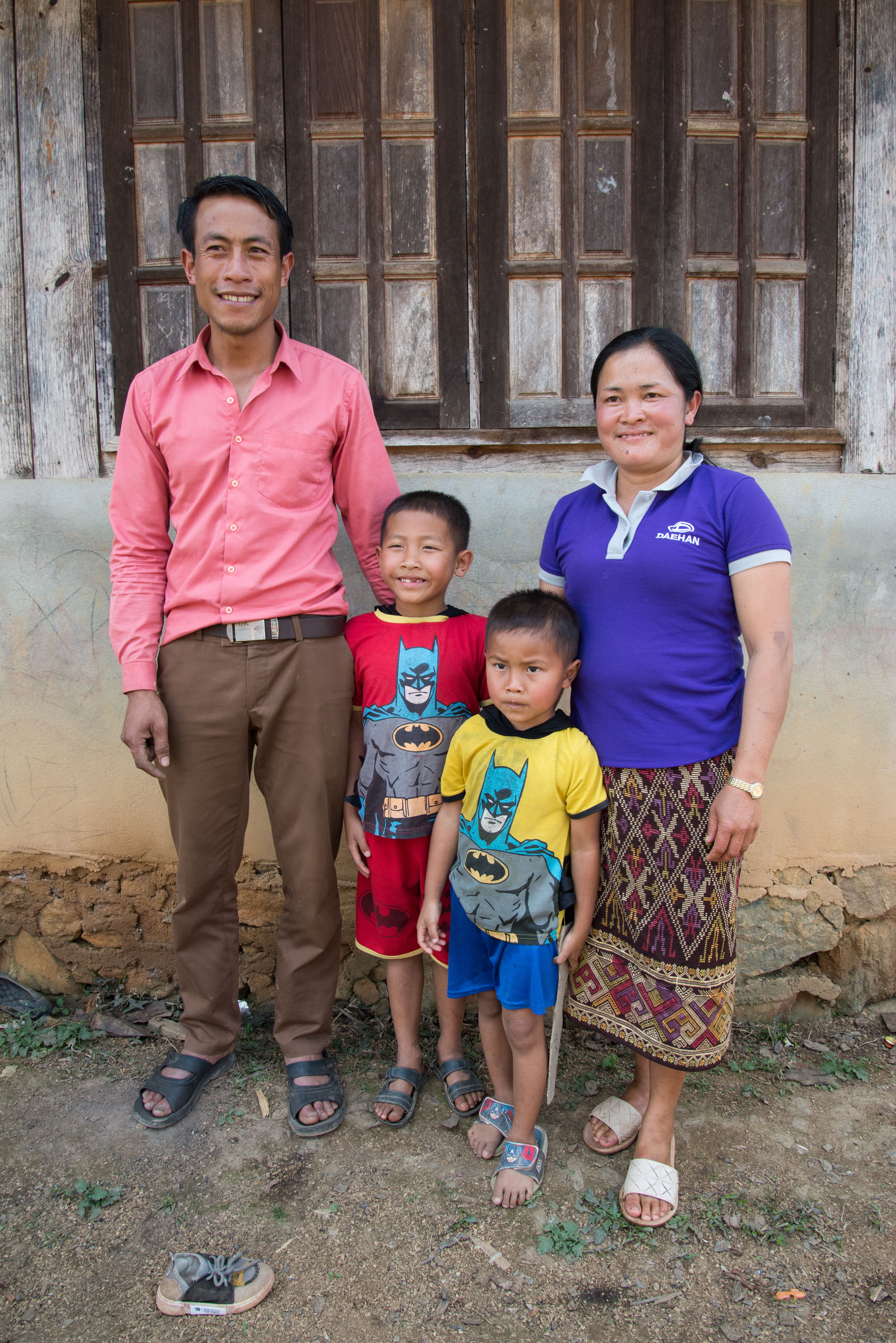 Artisan family of four poses together in front of a wooden building.