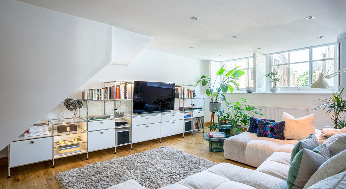 Modern living room with a TV, plants, and comfortable seating.