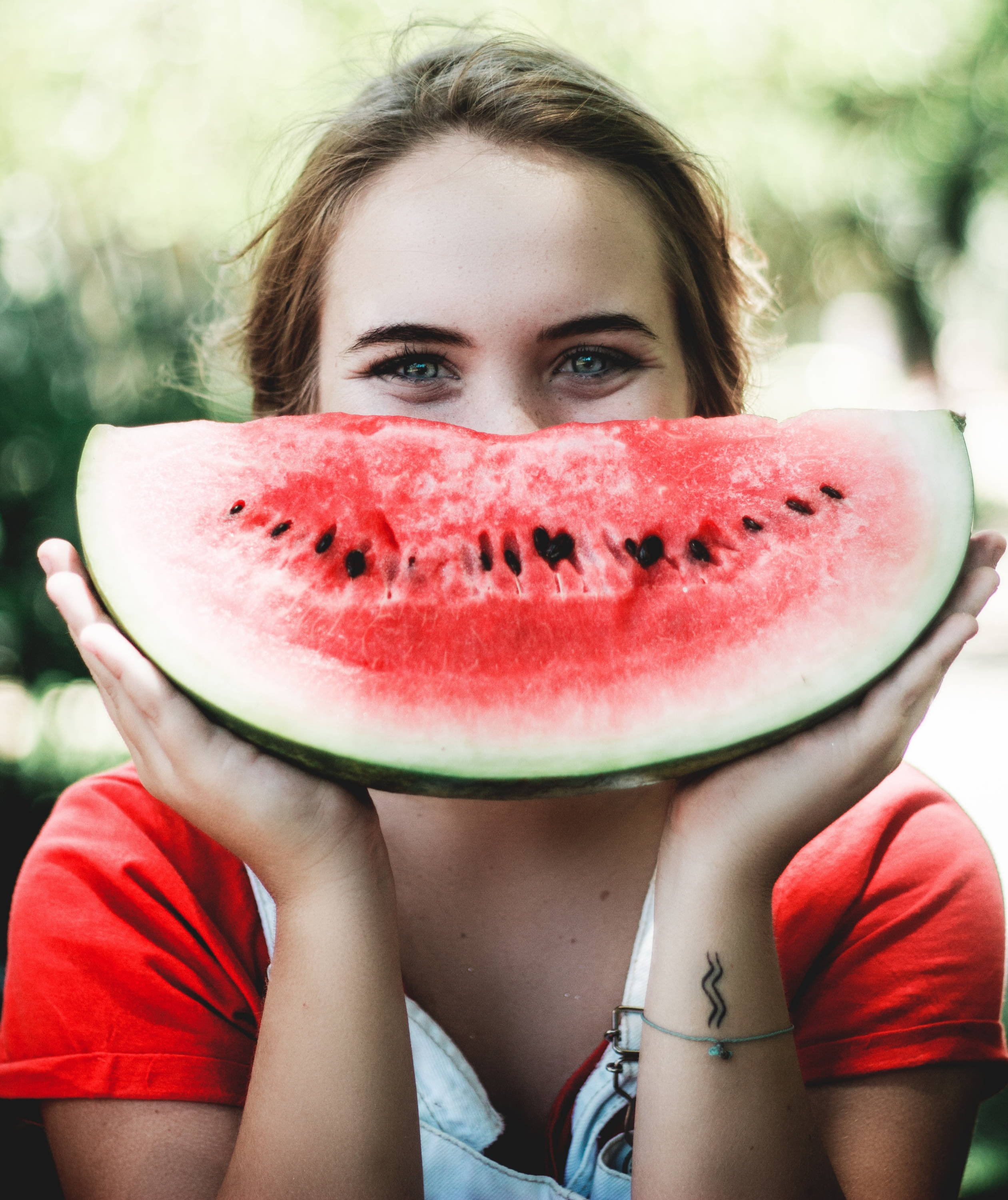 A smiling woman holding a giant slice of watermelon