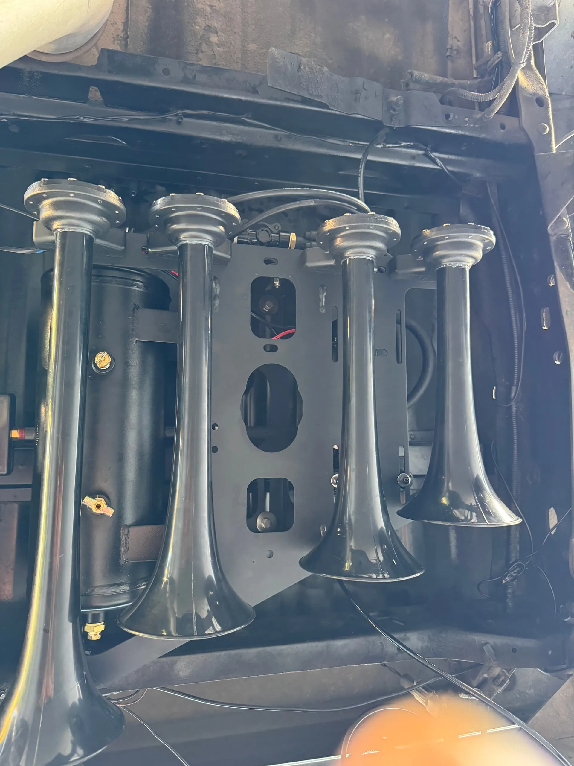Four black train horns and air tank mounted on a bracket under Noah's Ford F250