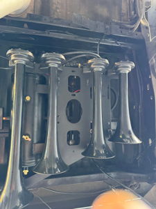 Four black train horns and air tank mounted on a bracket under Noah's Ford F250