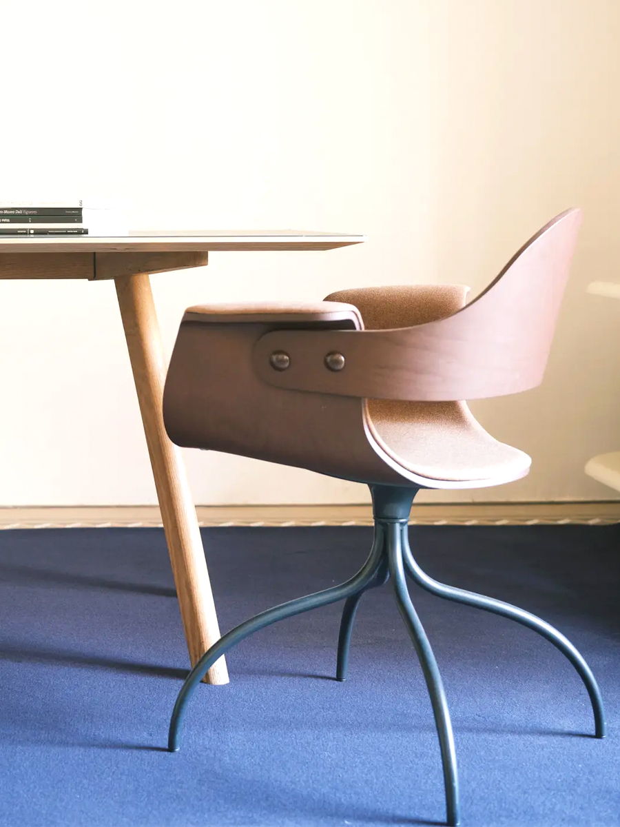 A modern Showtime Series Office chair by BD Barcelona beside a wooden table on a blue carpet.