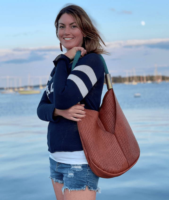 woman holding brown basketweave bag