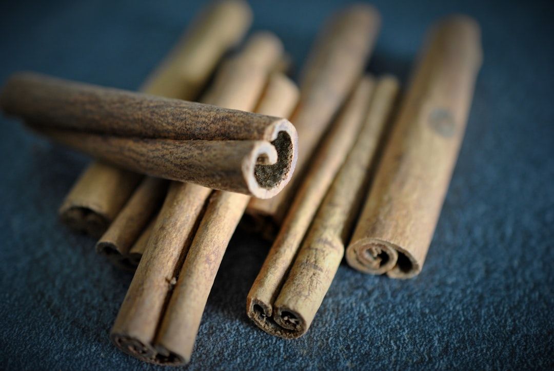 A pile of cinnamon sticks on a dark surface.