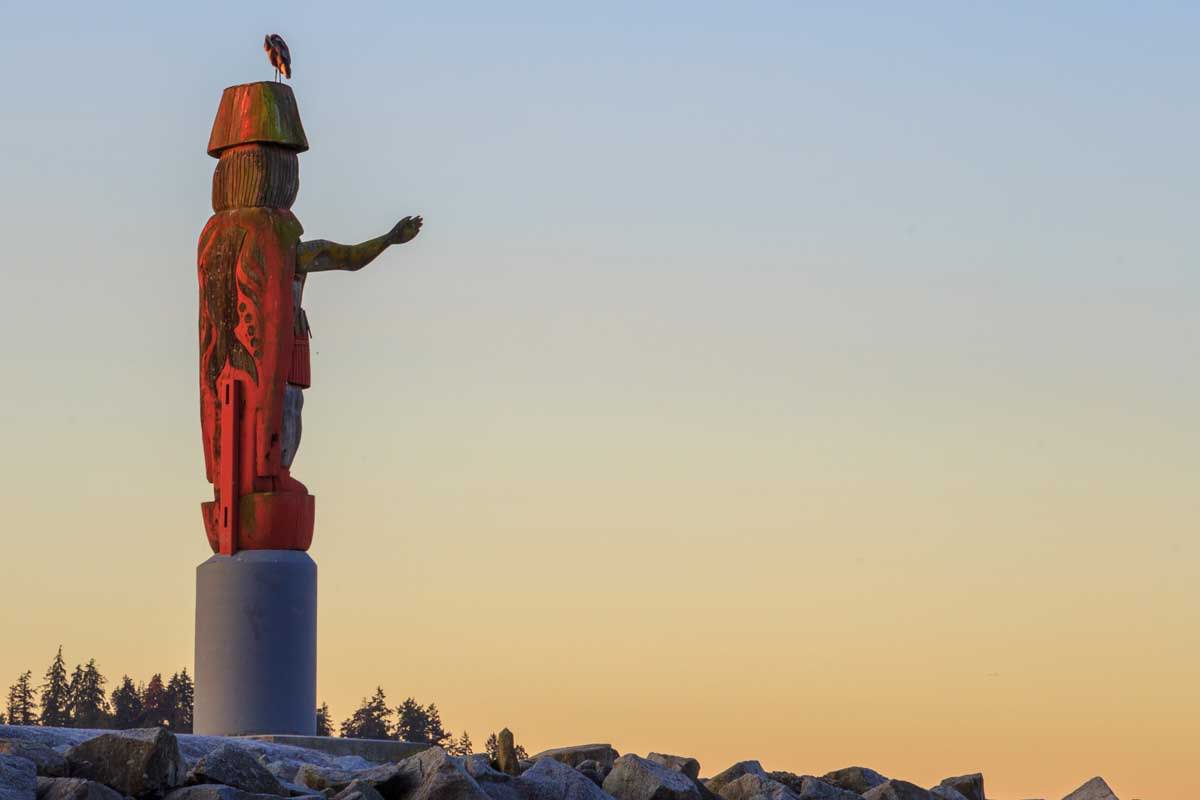 A Totem Pole on the rocks against a sunset sky