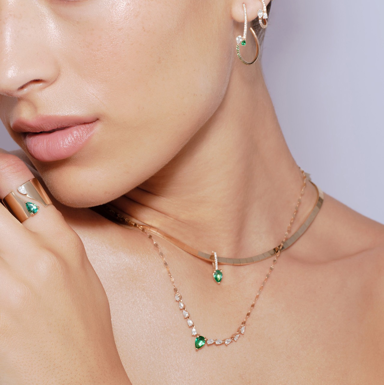 Close-up of a woman's neck and ear adorned with green gemstone jewelry.
