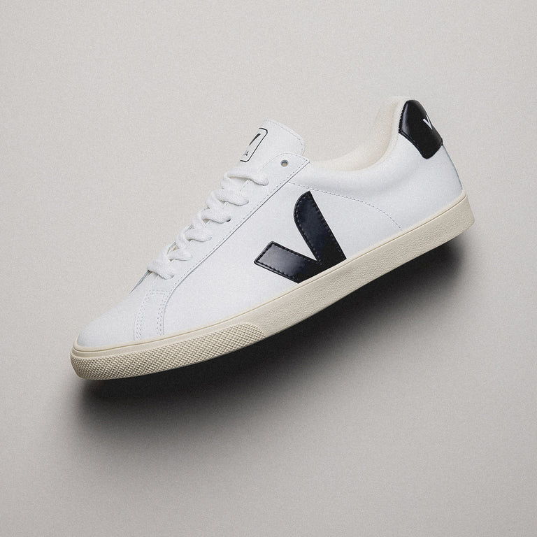 A white sneaker with a black logo and sole.