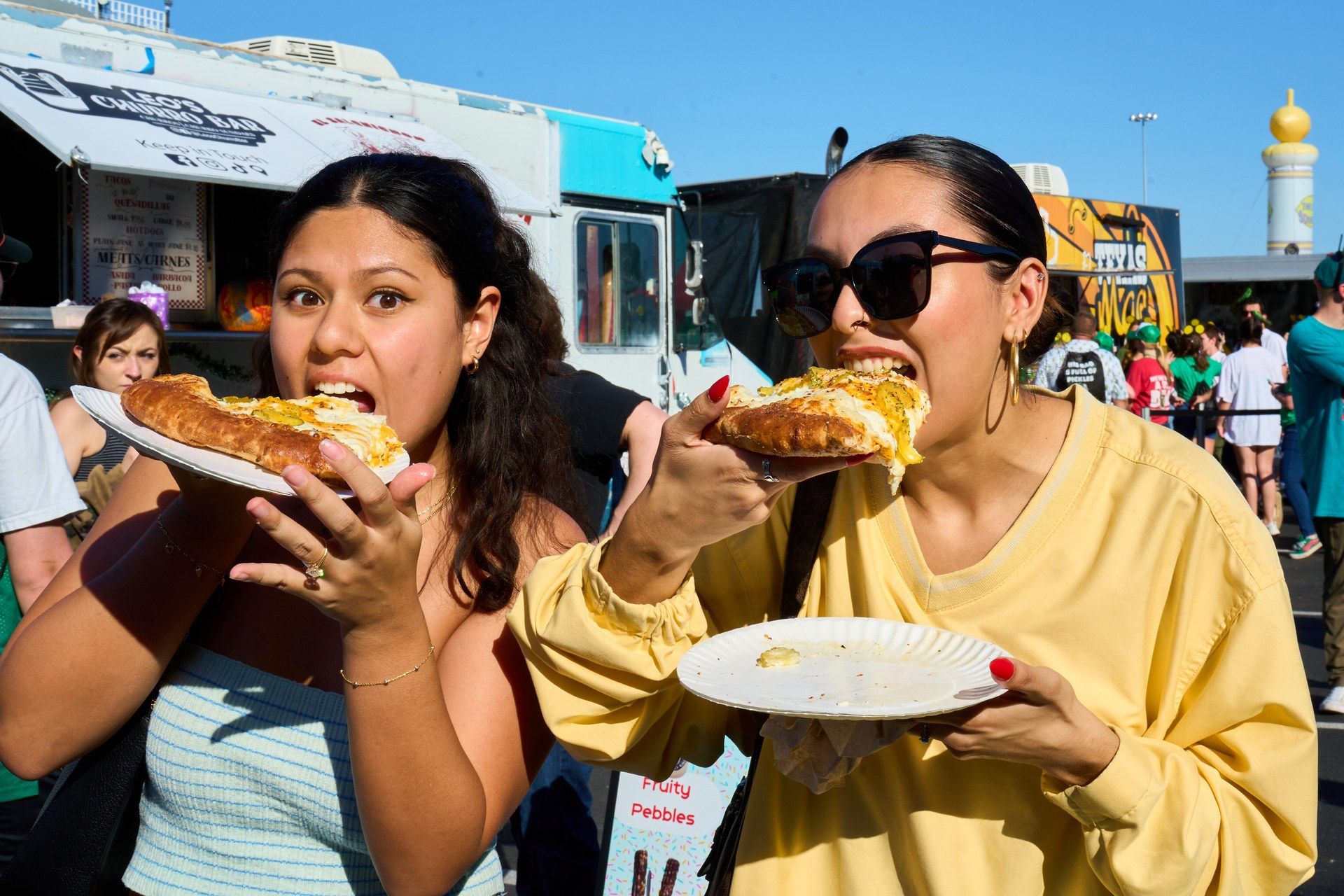 Two pickle lovers eat slices of pickle pizza at The Big Dill pickle festival, Globe Life Field and Texas Live!, Arlington Texas 2025
