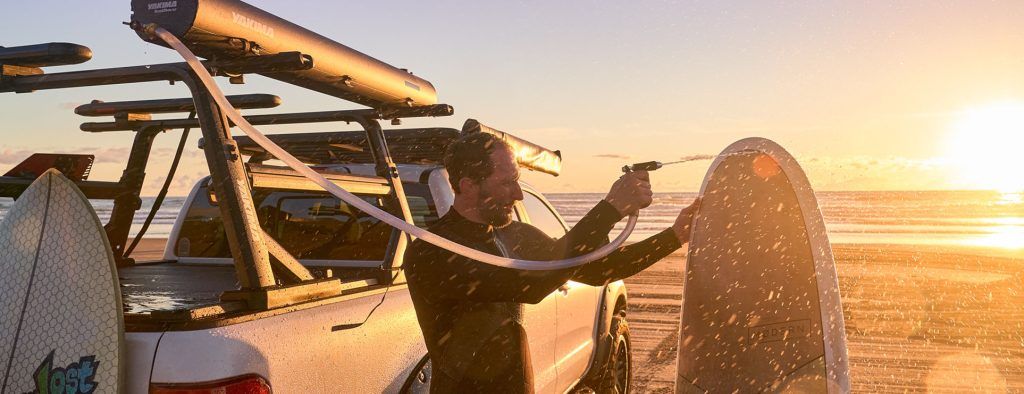 Ute with RoadShower and man hosing down a surfboard