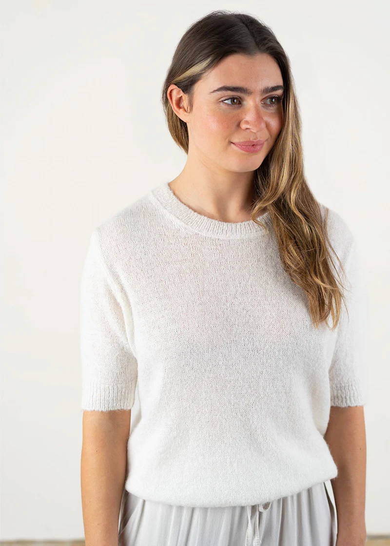 A model wearing a white, half sleeve knitted sweater
