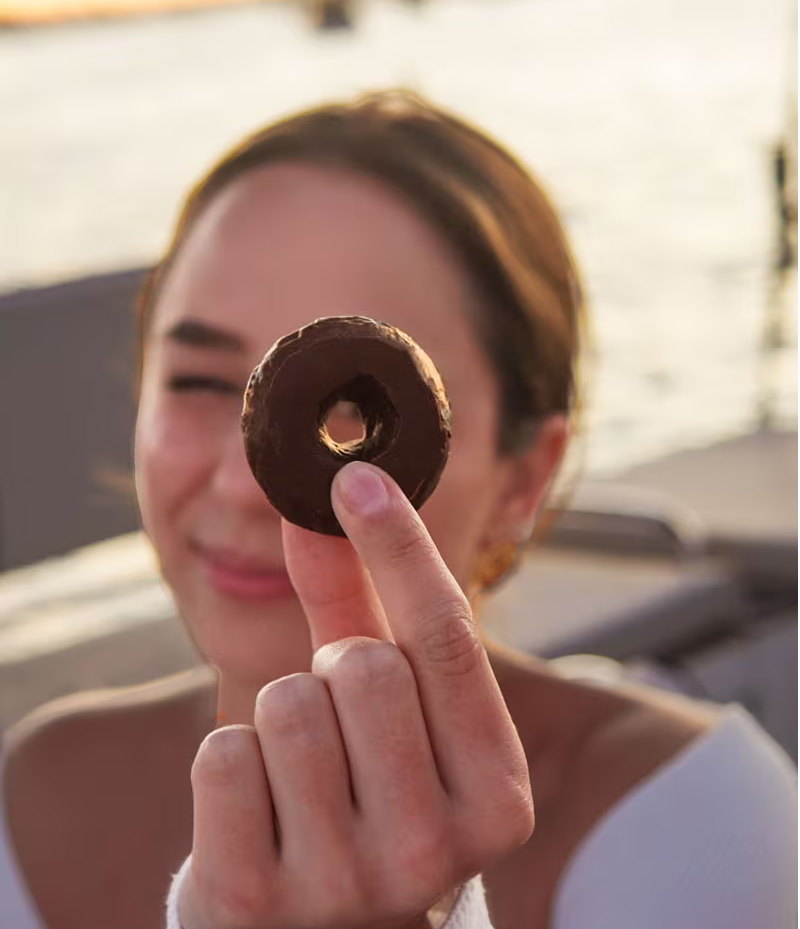 Woman holding chocolate donut to camera