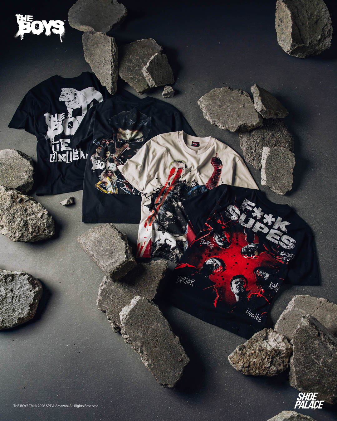 Four graphic t-shirts displayed among scattered rocks on a dark surface.