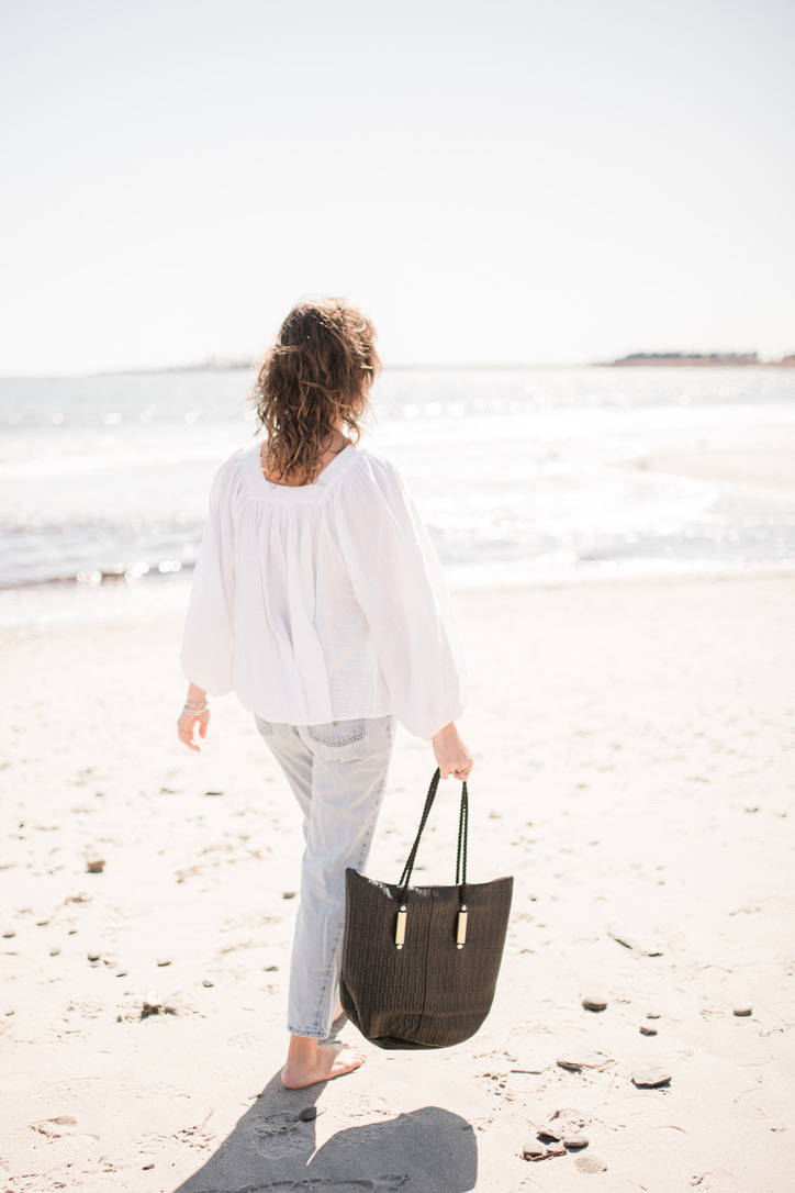 woman walking with black basketweave leather zip bag
