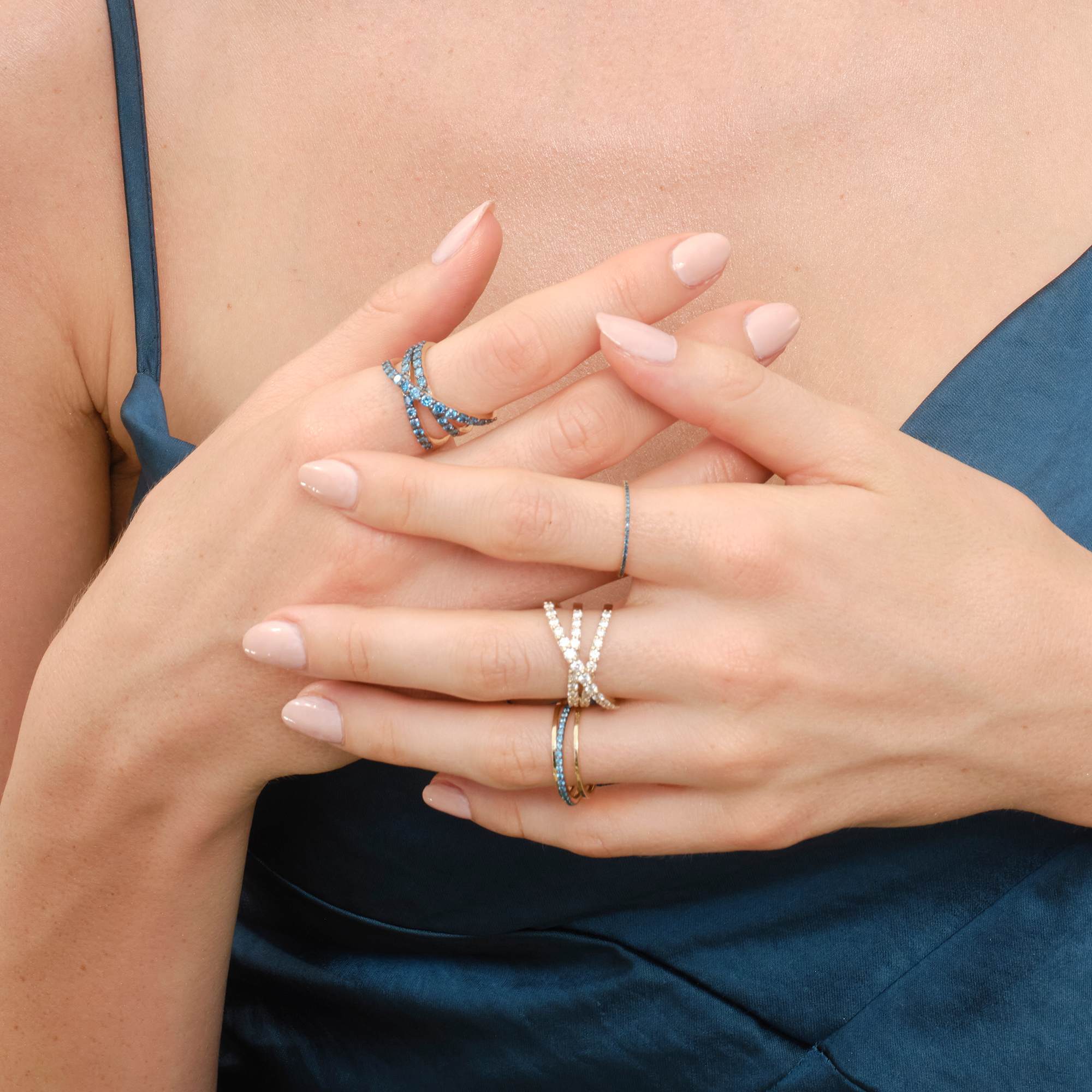 A close-up of elegantly manicured hands wearing multiple rings.
