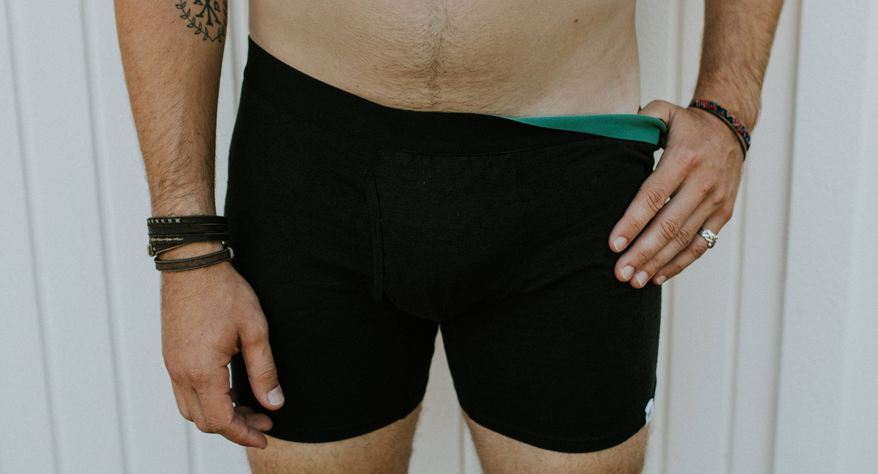 A man stands in WAMA hemp boxer briefs with one thumb pulling down the waistband.