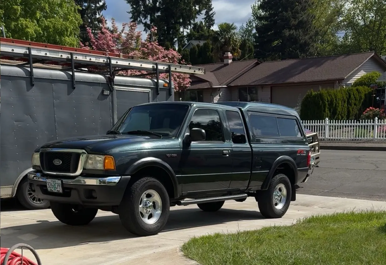 Front three-quarter Joshua's dark green Ford Ranger FX4 Off-Road with matching camper shell in driveway photo 2