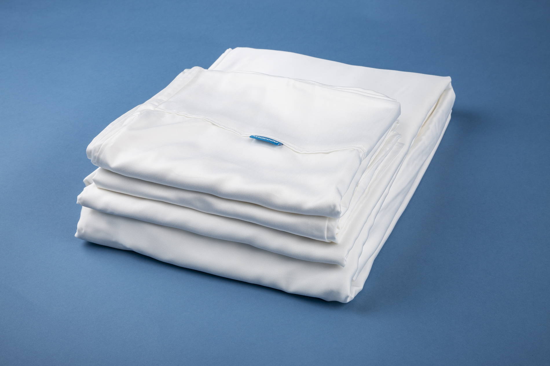 White silky bamboo sheets folded on blue background