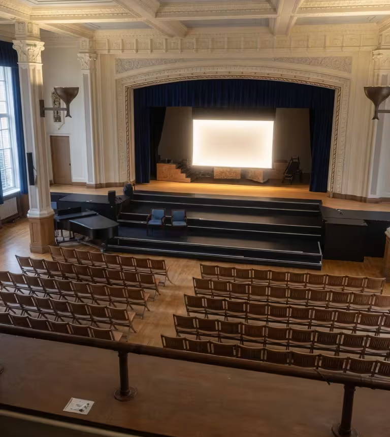 Interior view of a theater with empty seating and a stage.