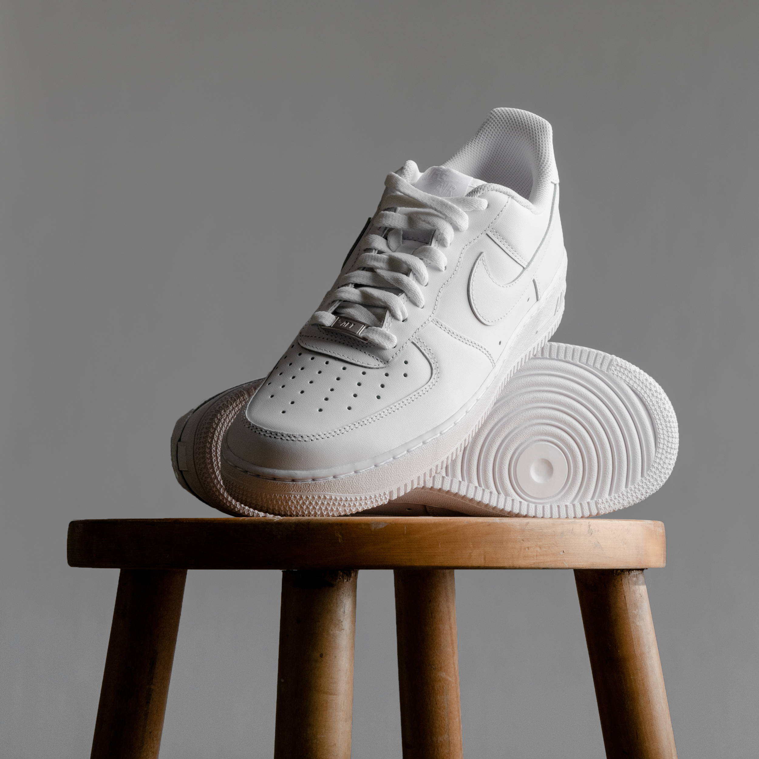 white nike air force ones stacked on barstool