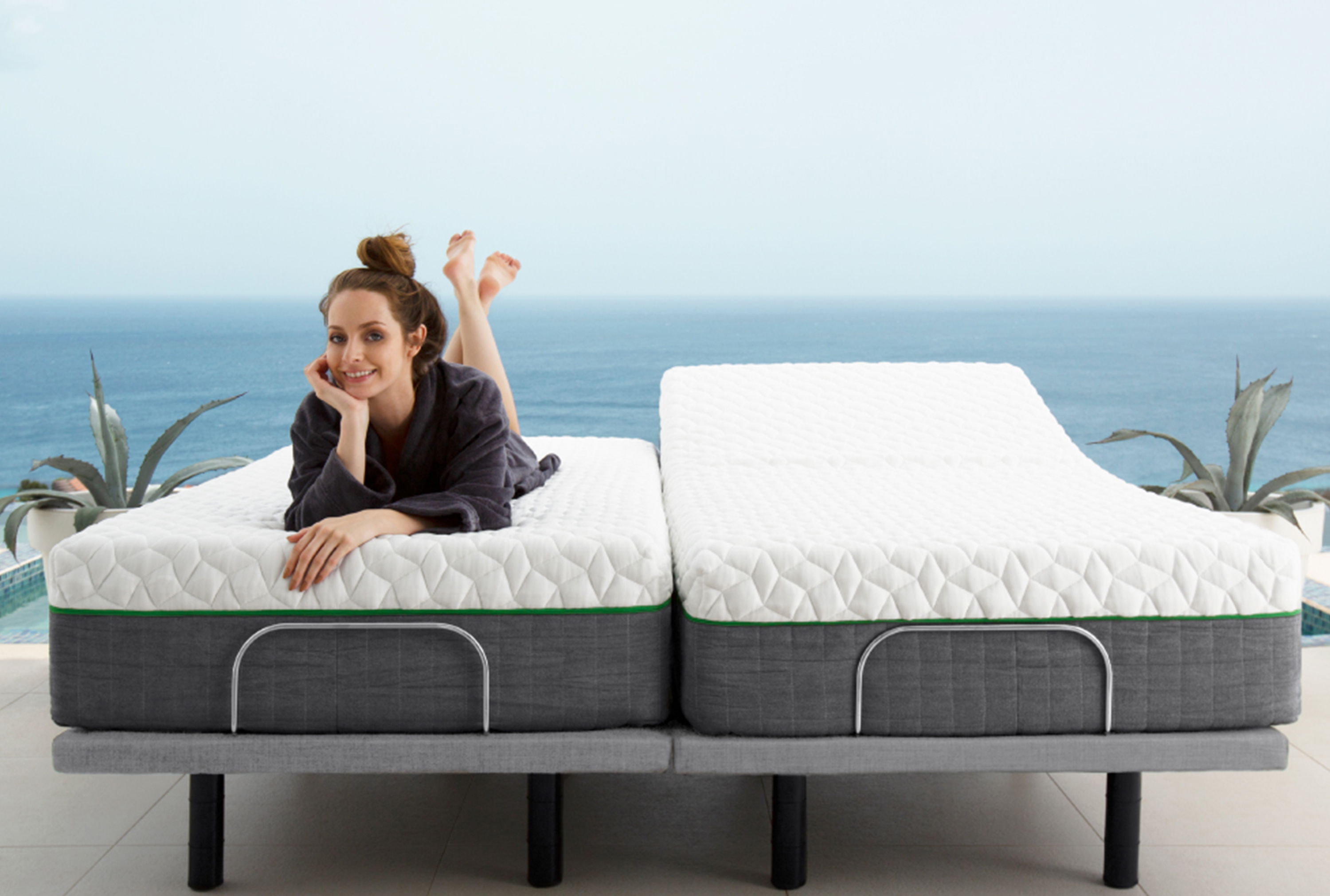 a woman lying on a split king mattress on a comfort base