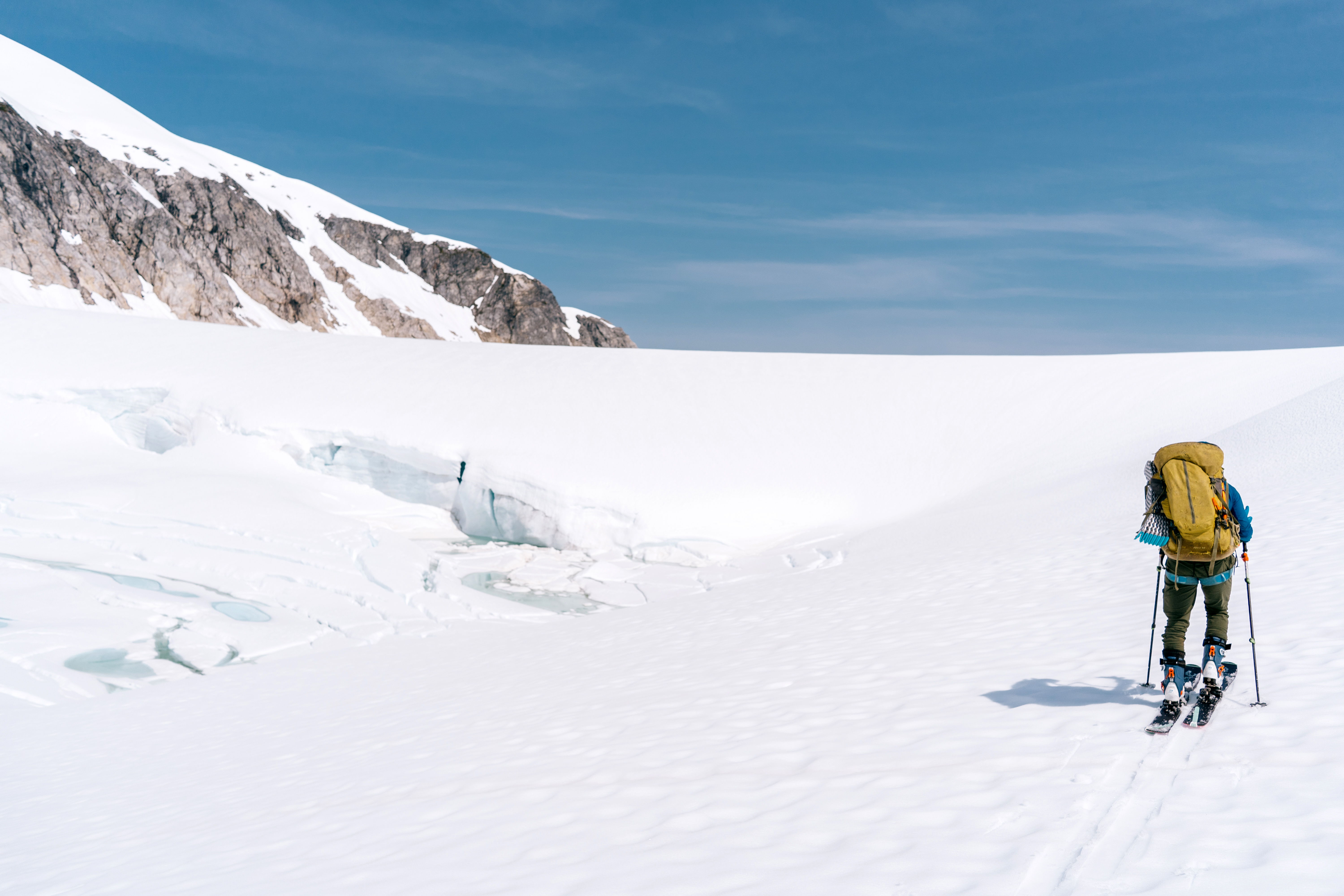 Person splitboarding on a snowy landscape with mountains in the background.