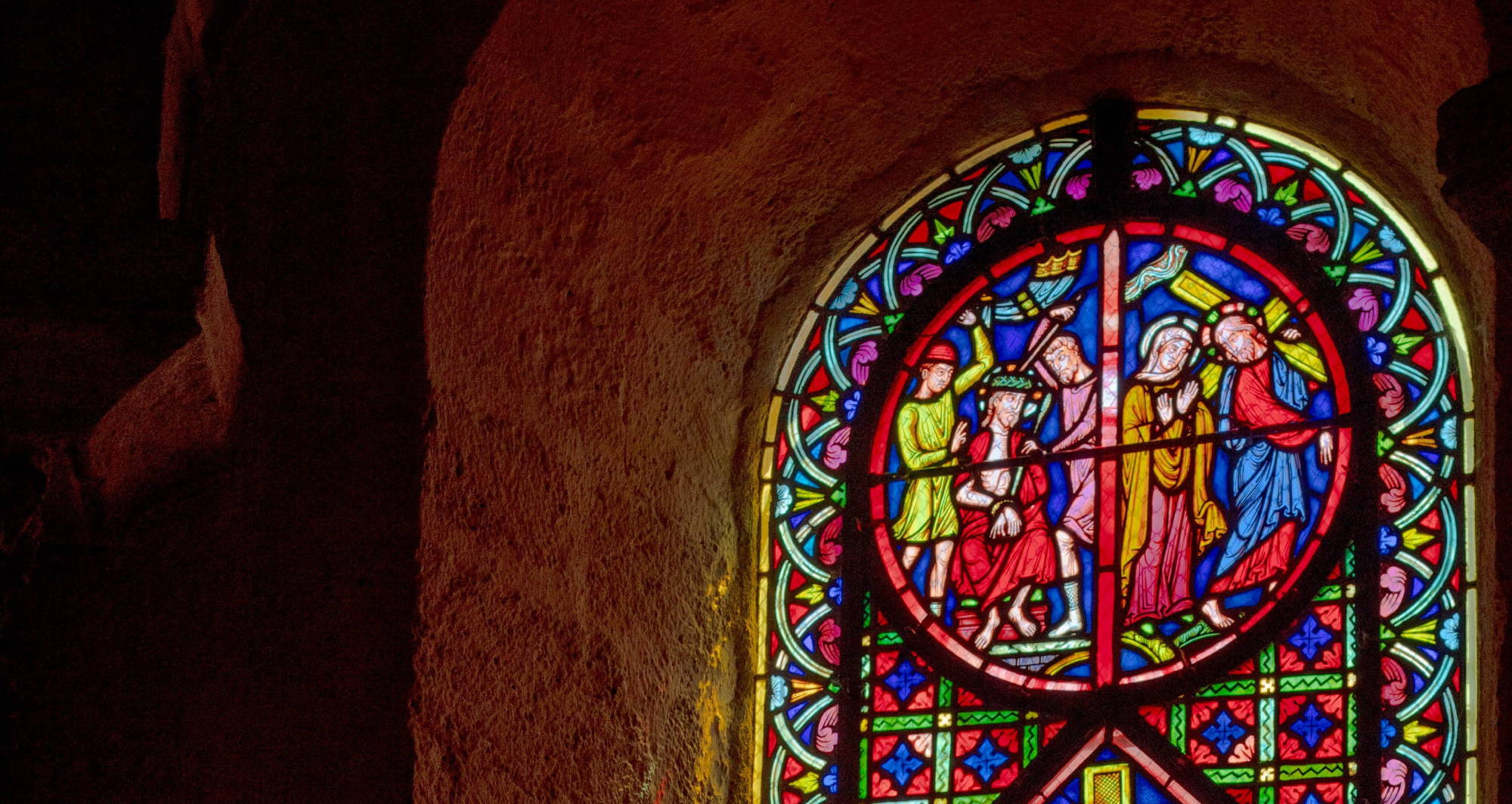  a colorful stained glass window light up in an old stone building