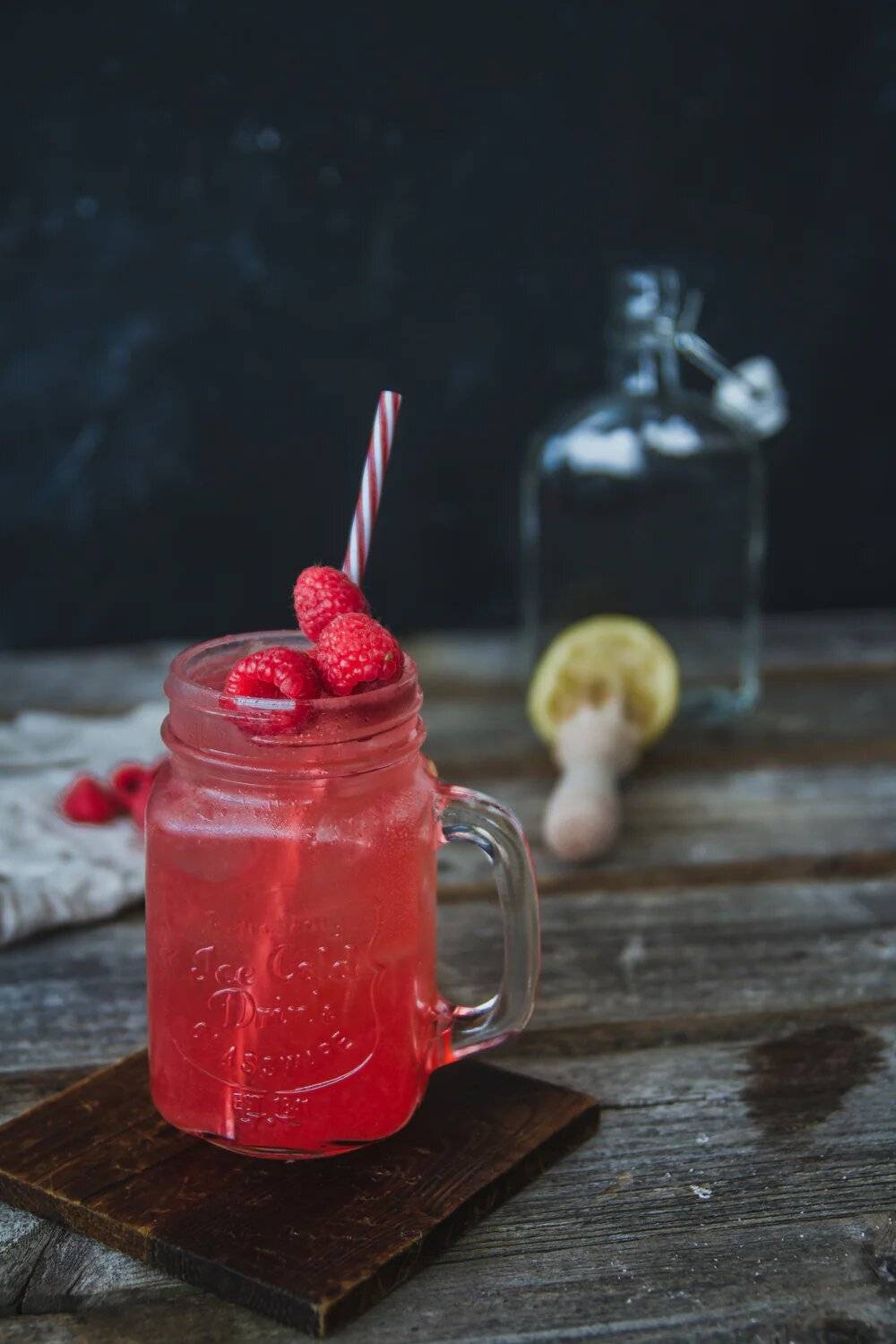 Raspberry cocktail in a mug with a straw and raspberries on top.