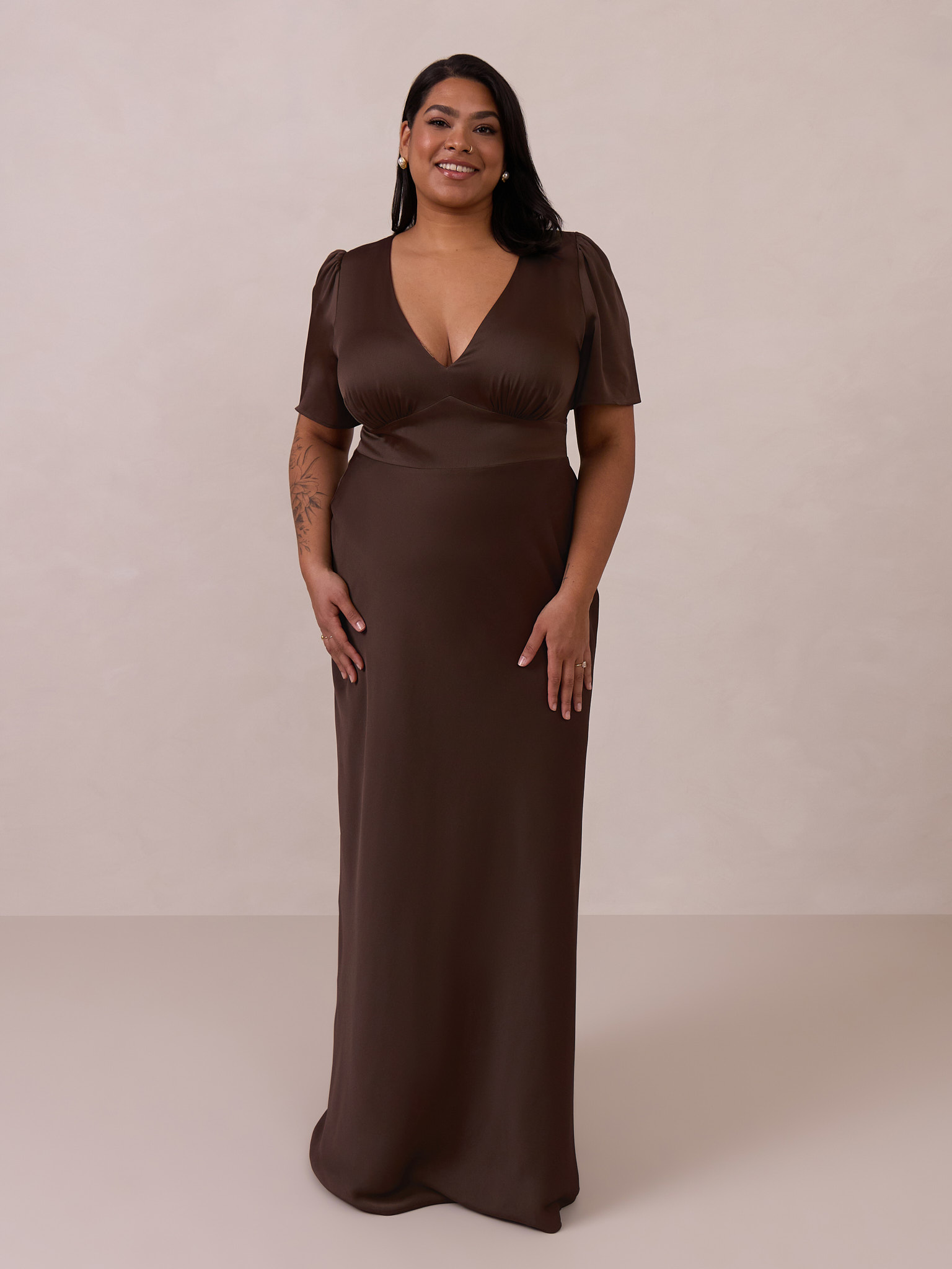 A woman wearing a brown evening gown against a neutral background.