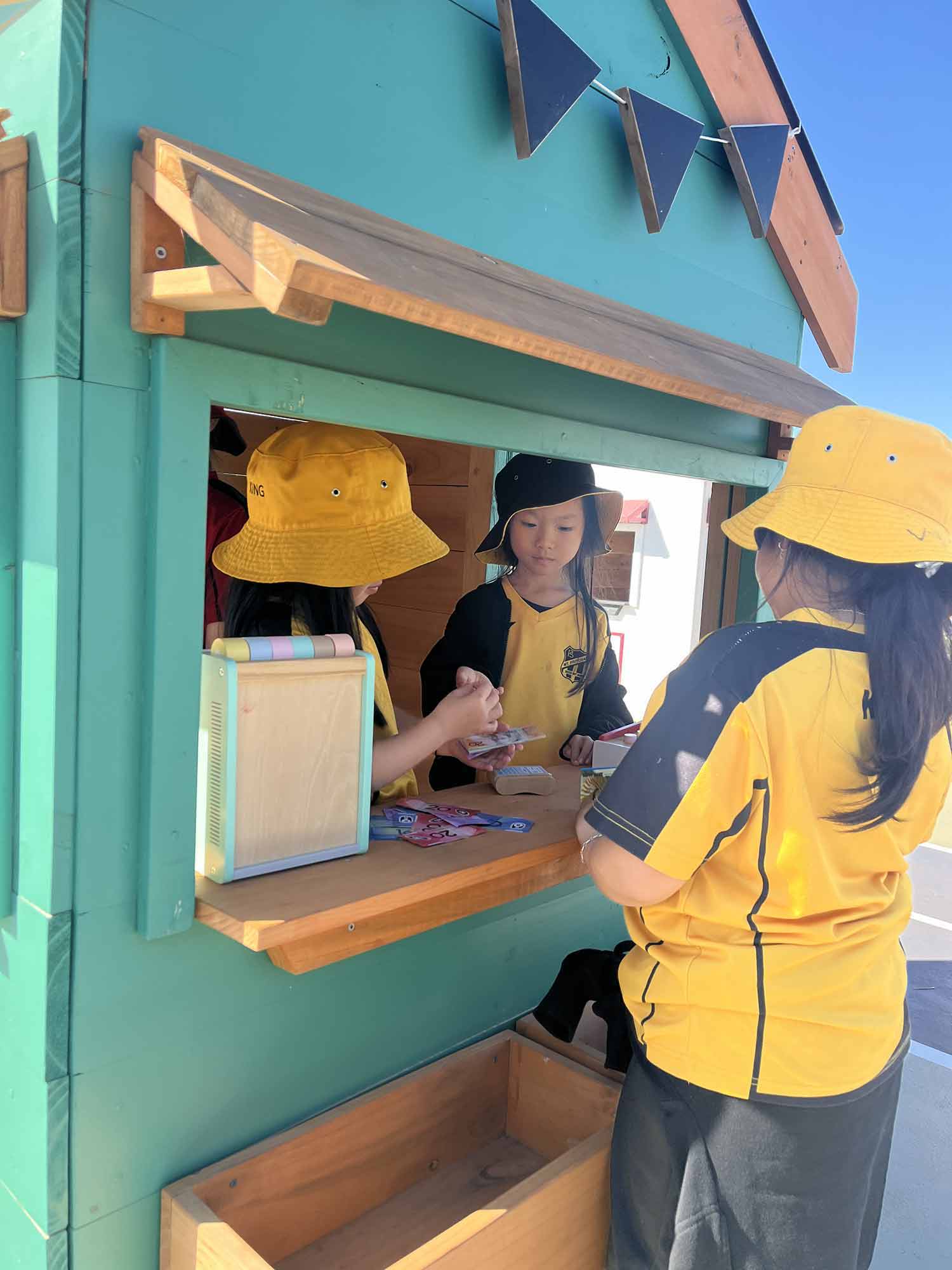 Kids role playing in their primary school wooden cubby house